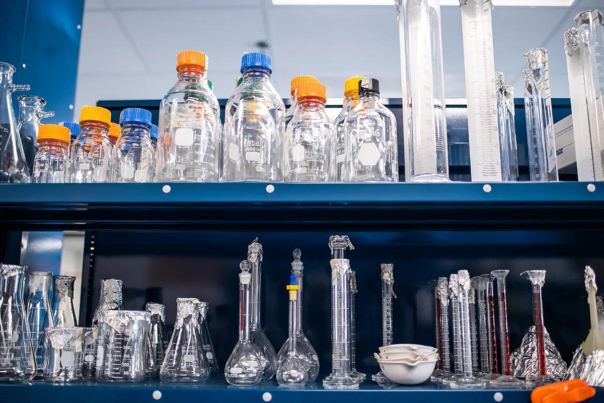 Rows of beakers and measuring glasses on a shelf in a research lab