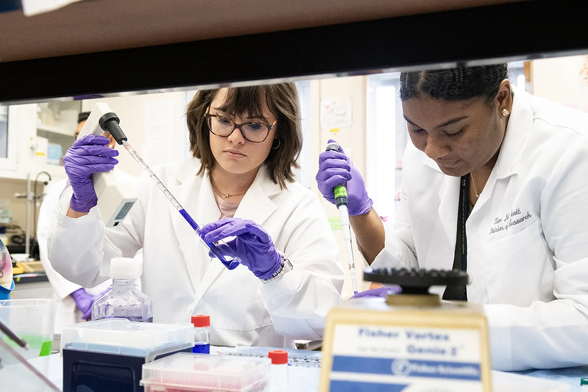 Two female students handling measuring tools in a research lab