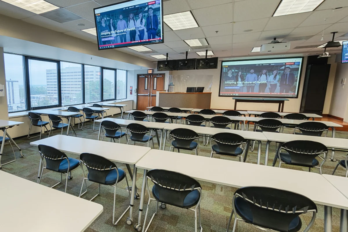 Wide view of rows of tables and chairs and televisions in one of the classrooms inside Rowland Hall