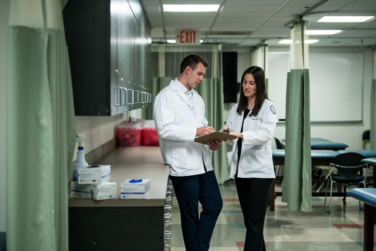PA Studies talk while looking at a clipboard of notes in the PA Studies Suite