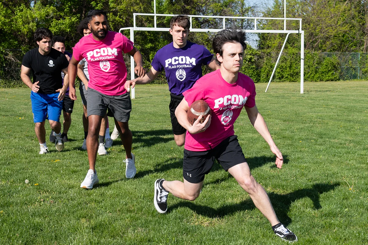Students playing flag football on the grass field
