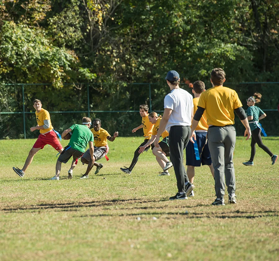 Grad students running and cutting during an intramural flag football match on PCOM's grass sports field
