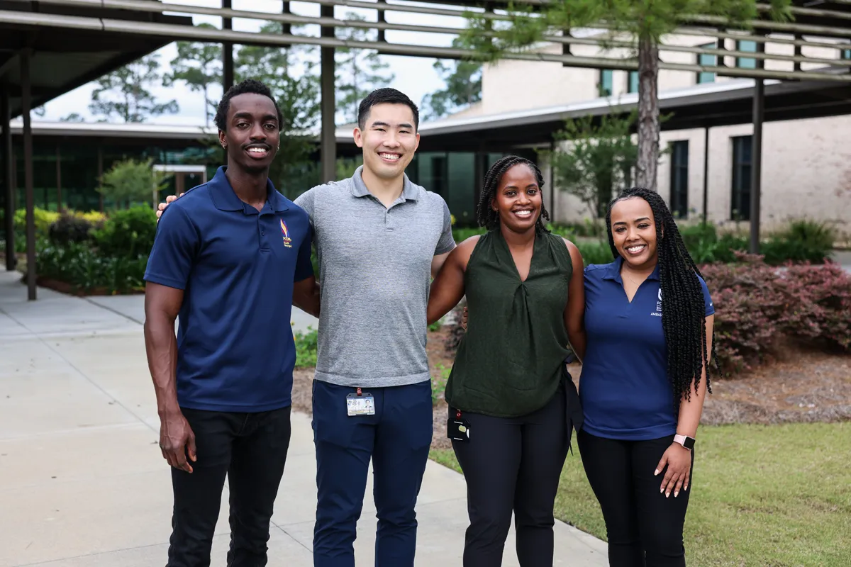 Grad students posing and smiling together with the Jeter Courtyard behind them