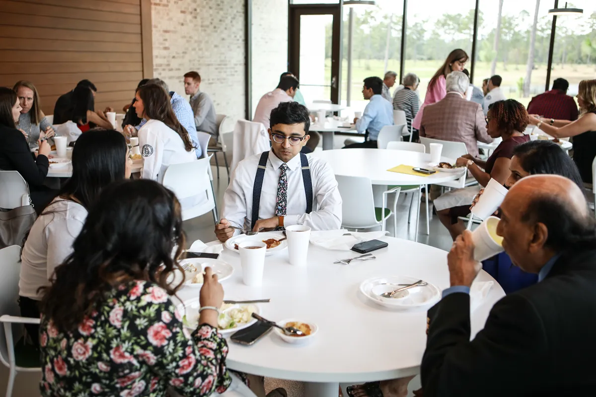 PCOM students and family members eating and talking in the Dining Area during an event