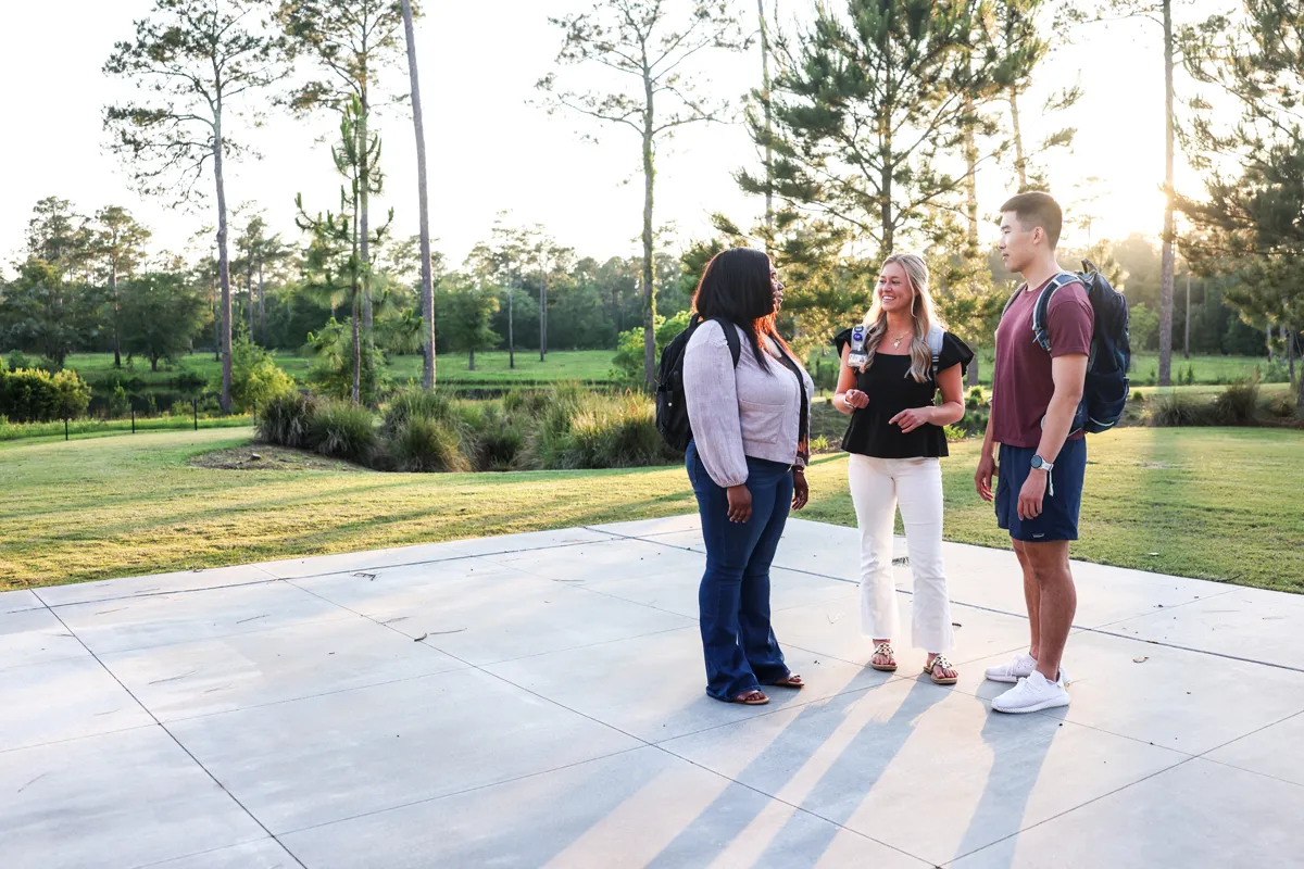 Med and grad students talk on a back porch while overlooking the pond and grounds behind PCOM South Georgia