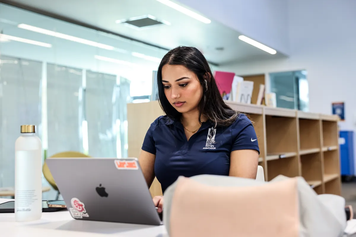 Grad student studying with a laptop inside PCOM South Georgia's library