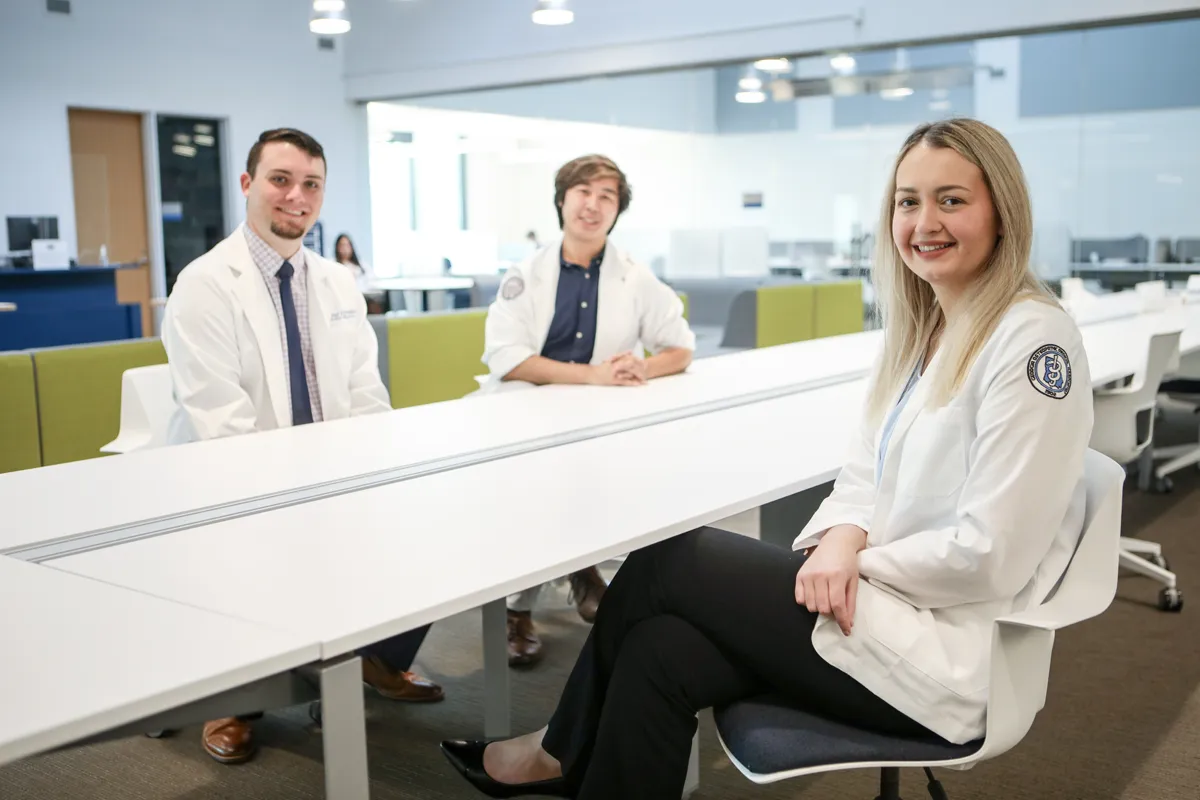 Med students smiling as they sit around at table in the Information Commons