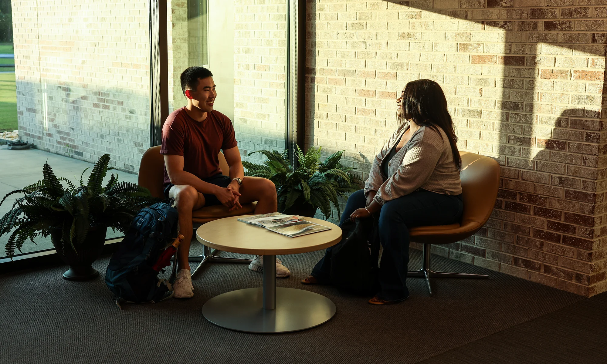 Two PCOM South Georgia students smiling while talking at a table in a lobby