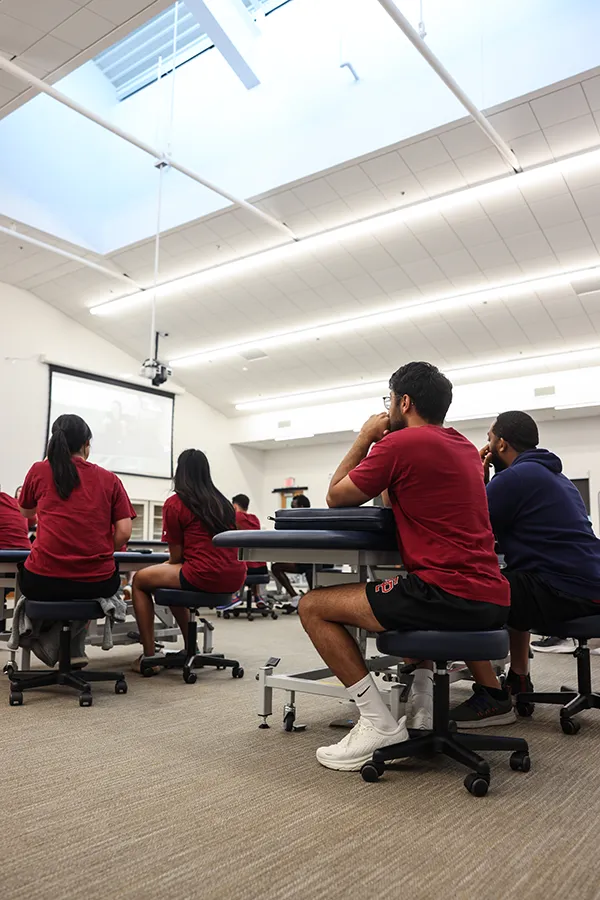 Angled view of med students listening to a faculty member in an OMM Lab