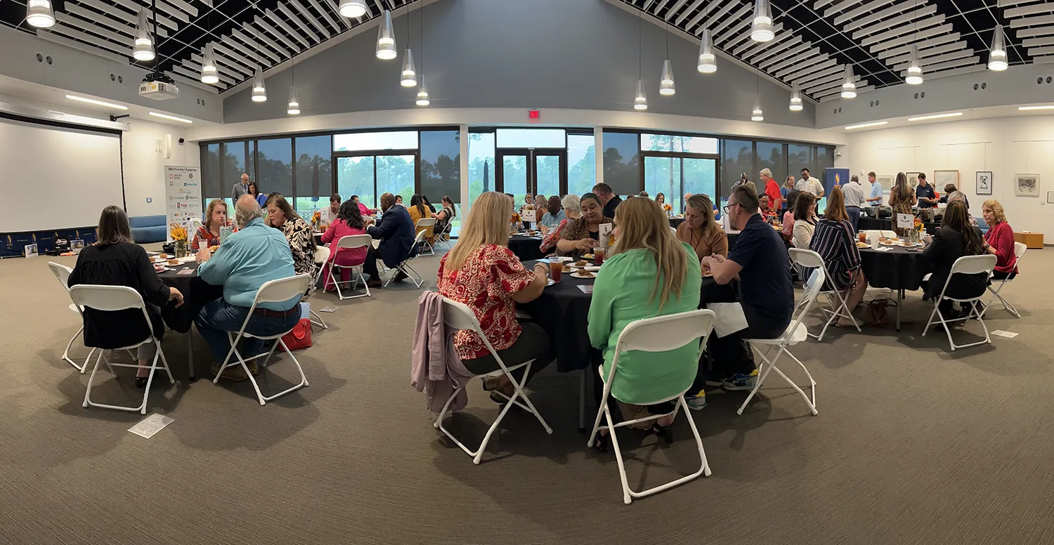 Wide panoramic shot of the SGB/DeLoache room filled with tables, chairs and people for an event at PCOM South Georgia