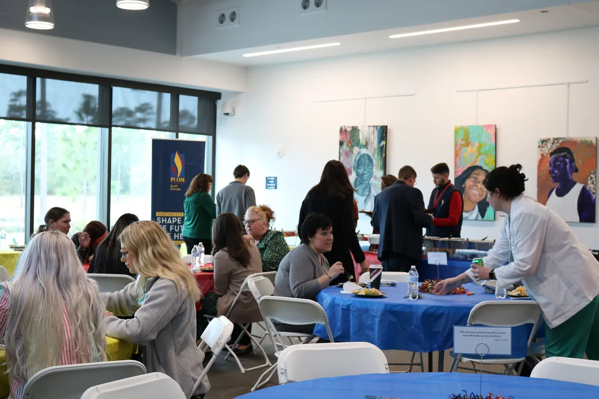 Students and staff sitting and enjoying a meal at decorated round tables in the multipurpose room