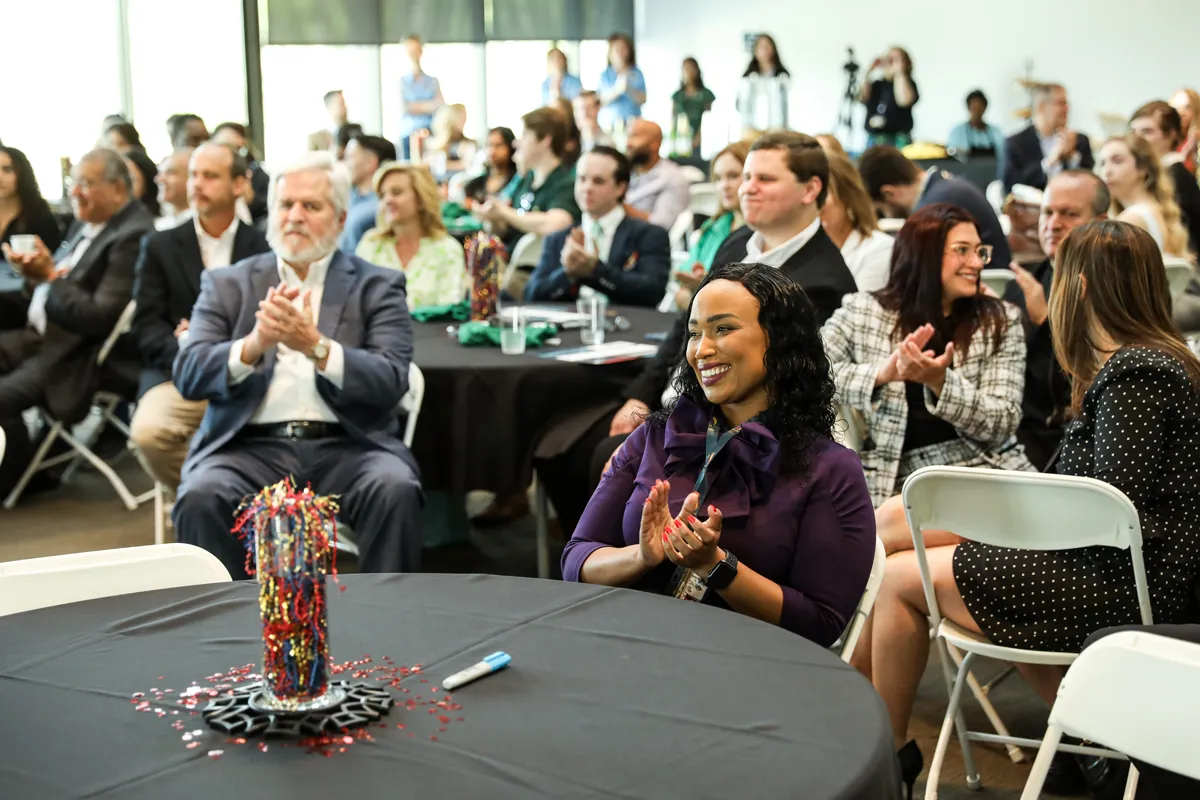 SGB/DeLoache room filled people smiling and clapping during a Match Day event