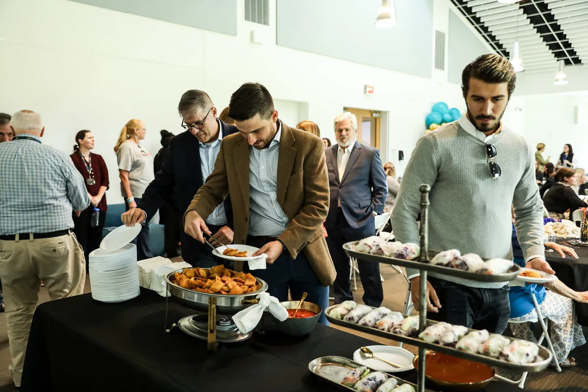 Guests sampling food from a caterer in the SGB/DeLoache Multipurpose Room at PCOM South Georgia