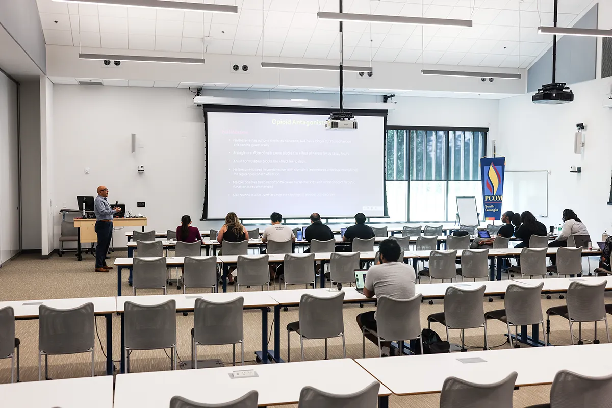 Faculty member teaching a couple rows of students in a large classroom at PCOM South Georgia