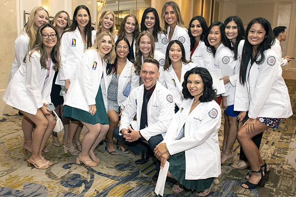 PCOM students pose for a group photo at a white coat ceremony.