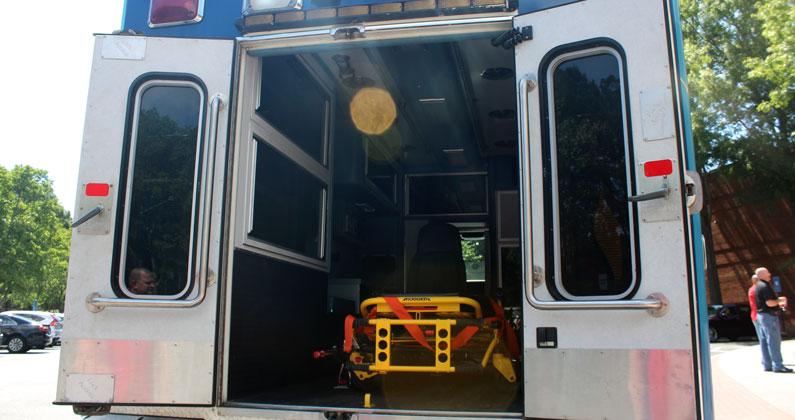 Rear view of the PCOM Georgia mobile medical laboratory. Double rear doors are opened, revealing a yellow gurney strapped inside the vehicle.