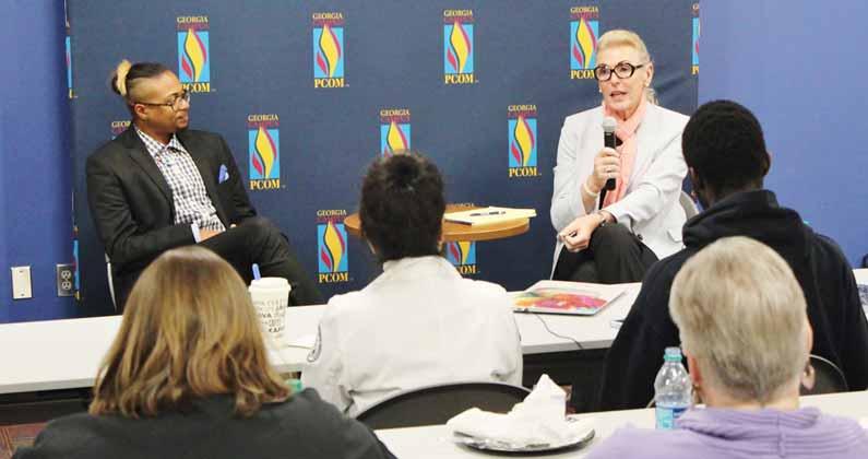 Dr. Anne Koch talks to a guest about transgender medical care issues in front of students in a PCOM classroom.