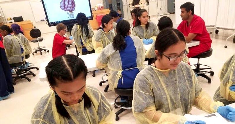 PCOM medical students and faculty teach high schoolers about anatomy in a dissection lab.