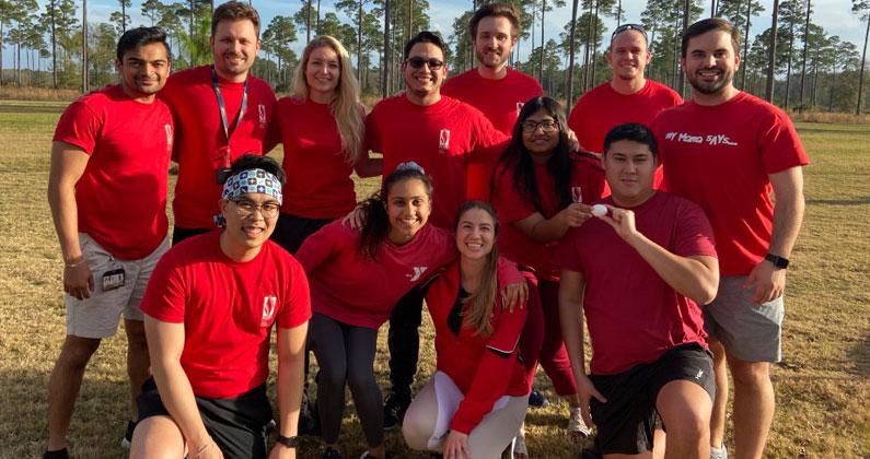 Men and women of the PCOM South Georgia DO class smile outside wearing red shirts during field day as part of orientation in August 2019.