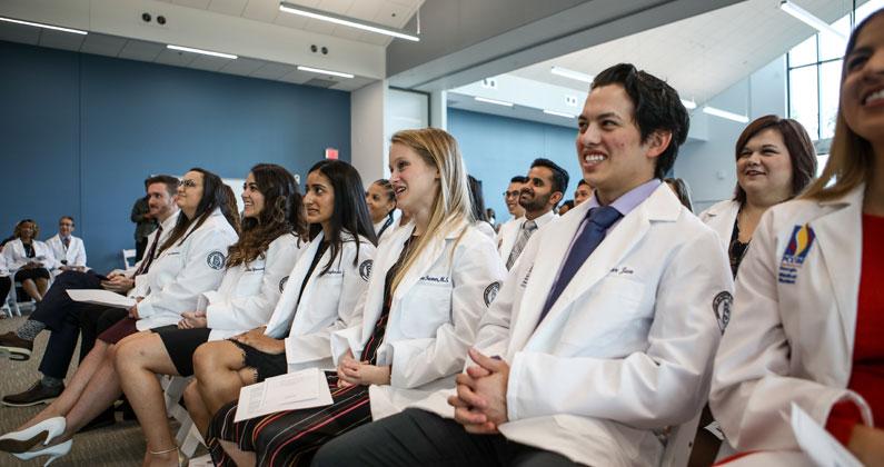 PCOM South Georgia med students sit and smile in rows of seats during the white coat ceremony in October 2019.