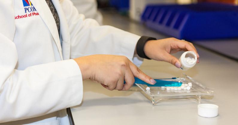Pharmacy student sorts pills in a pharmaceutical lab at PCOM Georgia.
