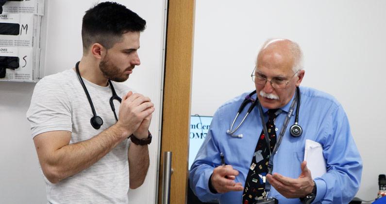 Dr. Fredrick chats with a medical student during a primary care skills lab.