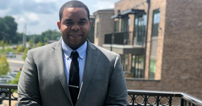 PCOM Georgia pharmacy student Jeffrey Clark (PharmD '21) wears a suit and smiles on his apartment balcony.