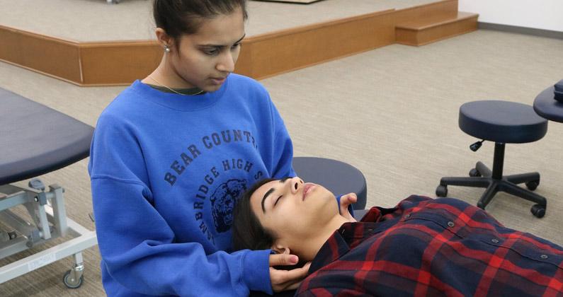 A PCOM South Georgia DO student performs a neck stretch technique on a fellow student in an OMM lab.