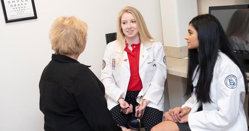 Osteopathic medicine students talk to a patient actor in an exam room during a simulation exercise.
