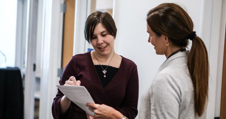 Dr. Petree talks to another faculty member in a hallway at PCOM South Georgia in Moultrie.