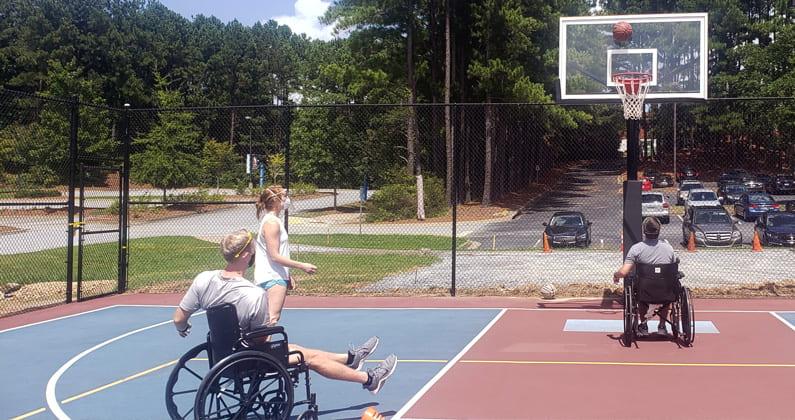 PCOM Georgia PT students shoot hoops while using wheel chairs so they can learn more about adaptive sports.