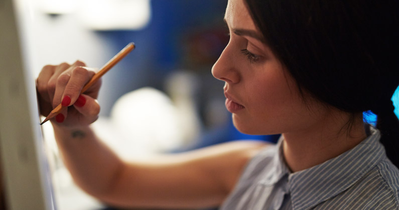 Medical student uses a pencil to draw on a canvas.