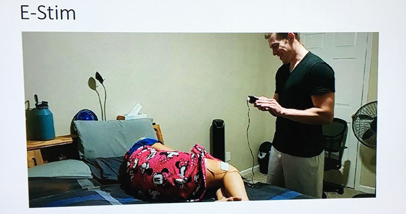 A PCOM Georgia PT student practices e-stim therapy on a roommate during online learning sessions due to COVID-19.