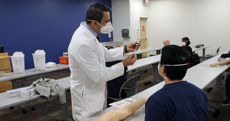 A PCOM Georgia professor teaches medical students how to safely use syringe for administering COVID-19 vaccinations.