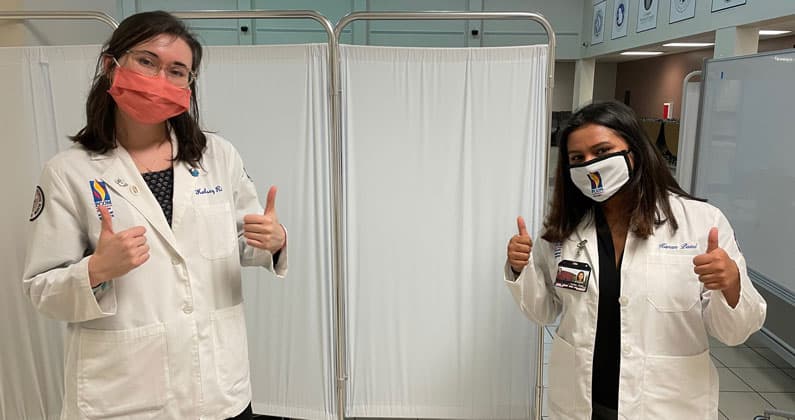 Two PCOM Georgia medical students are shown at a Covid-19 vaccination site.