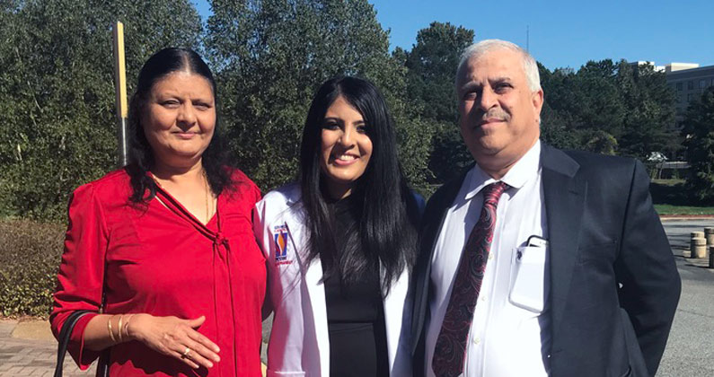 Kinjal Shah, PharmD, poses with her family in her student physician's white coat.