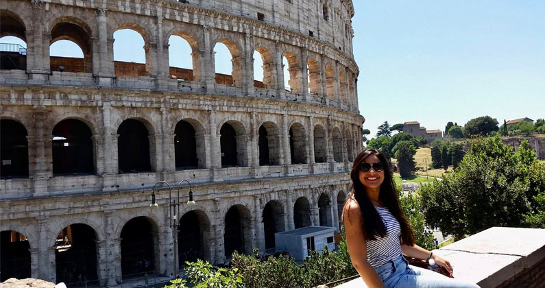 Vivian Flores, PharmD, smiles as she poses in front of the Roman Colosseum.