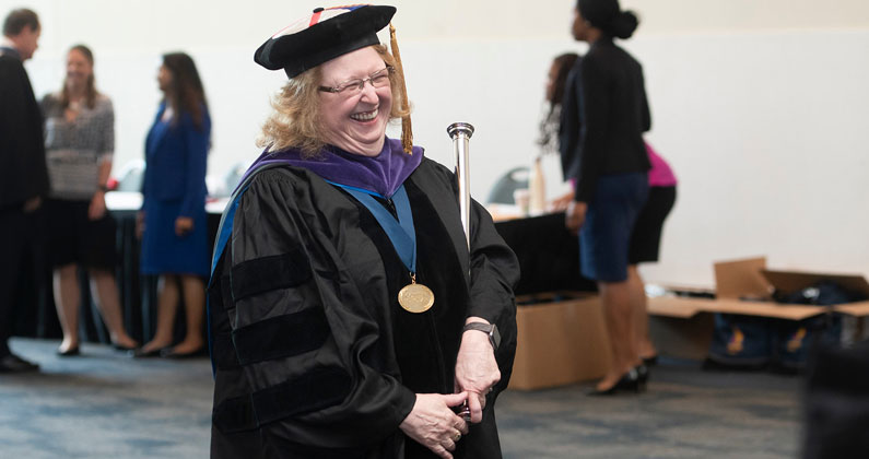 Dr. Owen walks in commencement regalia.