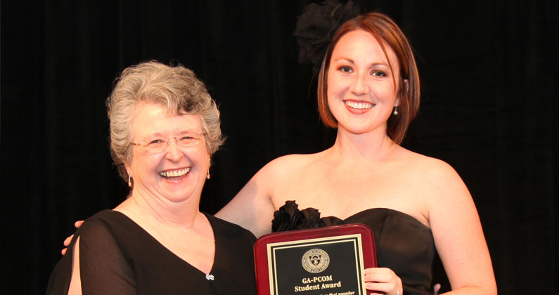 Mary Owen smiles with a medical student during an award ceremony.