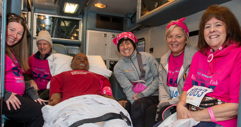 PCOM faculty and staff smile with mannequins and simulation equipment at the Paint Gwinnett Pink 2022 event.